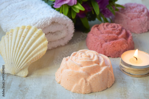 Rose shaped bath bombs for shower on a table, towel, seashell and candle