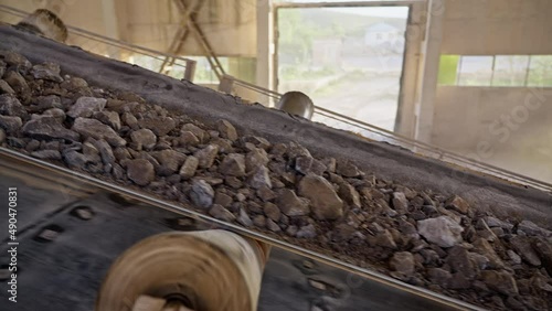 The stone ore moves along a belt conveyor. The minerals after the crushing machine are moved along the conveyor belt in the factory.