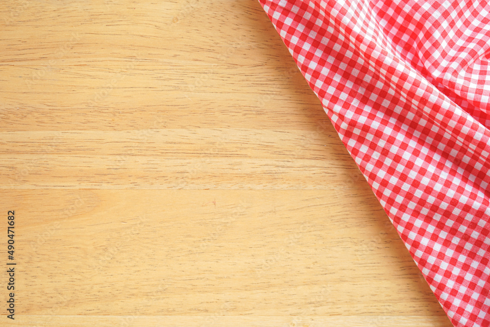 Wood table background with crumple pink plaid fabric or tablecloth in the corner Wood table background with crumple pink plaid fabric or tablecloth in the corner