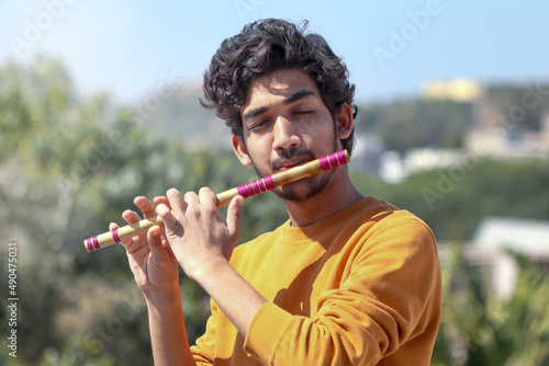 Indian boy playing bansuri Indian Bamboo Flute.