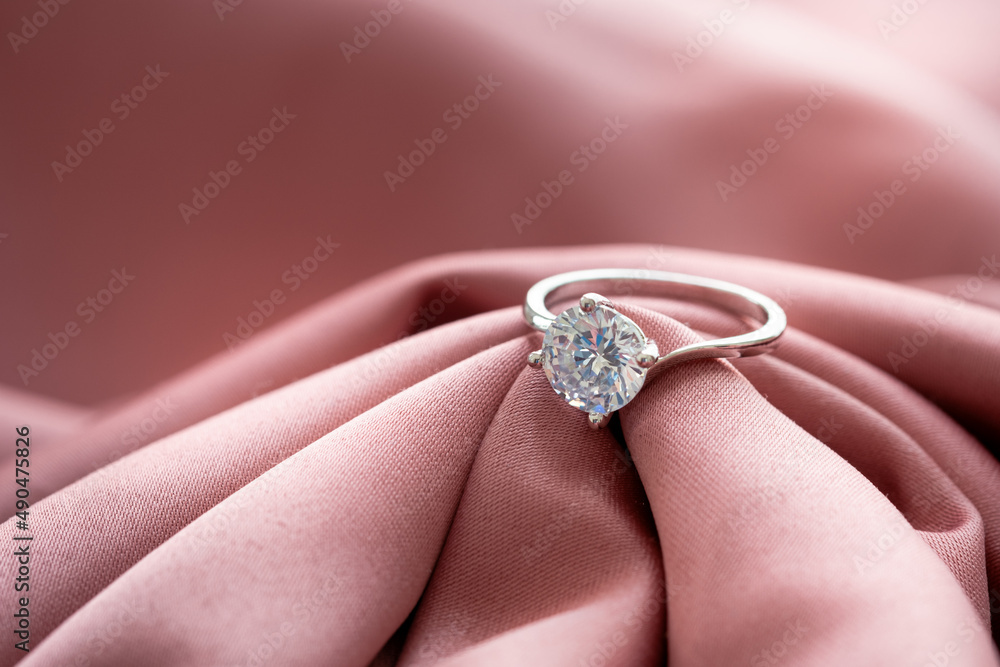 The wedding diamond ring is placed on a pink gold cloth. The wedding diamond ring is placed on a pink gold cloth.