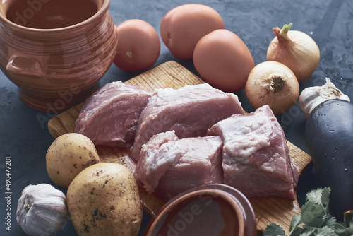 pots for cooking chanakhi and ingredients meat tomatoes potatoes garlic eggplant on the table photo