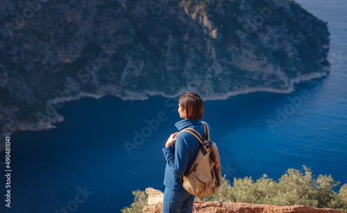 Butterfly Valley (kelebekler vadisi) in city of Oludeniz Fethiye in western Turkey. You can only reach this valley by boat or rock climbing. woman looks down on sea from cliff. photo
