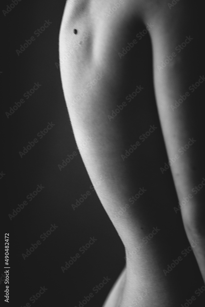 Fototapeta premium Body details close-up, nude female body. Nude skin photography in black and white. Light defocus and art noise on the frames