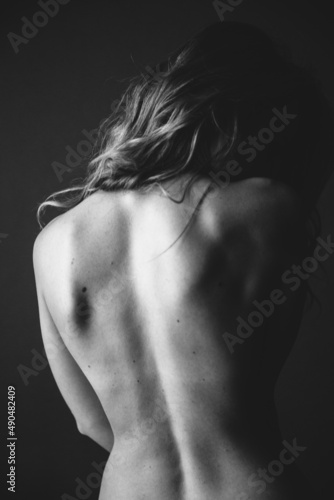Body details close-up, nude female body. Nude skin photography in black and white. Light defocus and art noise on the frames.Silhouette of a woman's bare back
