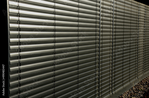 blinds on the wall of the glass building covers the window and the shadow from sun interior building.grey gold color.metal strips connected by strips of cables automatically controlled, jalousie