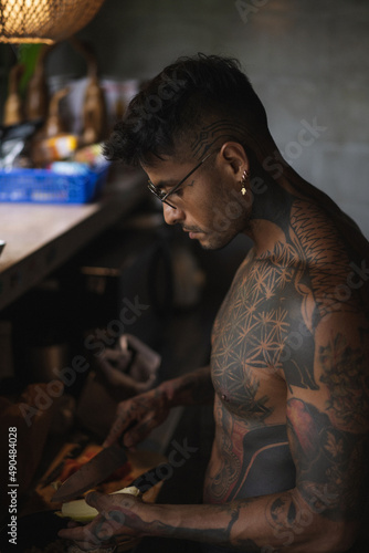 Wallpaper Mural Young authentic latin american tattoed man standing in the kitchen, preparing a breakfast and holding a bowl of oatmeal. Torontodigital.ca