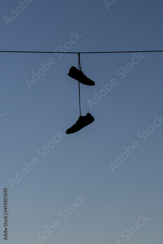 Scarpe appese ad un filo della luce con cielo blu photo