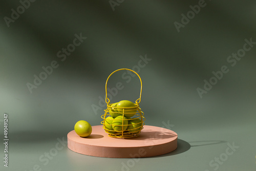 Easter eggs into the  yellow basket onbeige modern podium at green background with shadow. Copy space photo