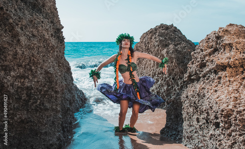 Gorgeous woman dressed in traditional Hawaiian dance attire enjoying views of a spectacular paradise beach