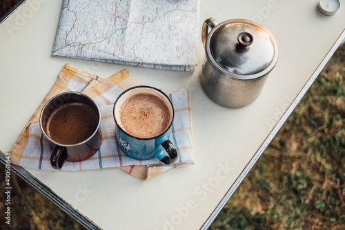 Fototapeta Naklejka Na Ścianę i Meble -  Two Mugs With Hot Drinks On The Table With Other Camping Equipment Close Up