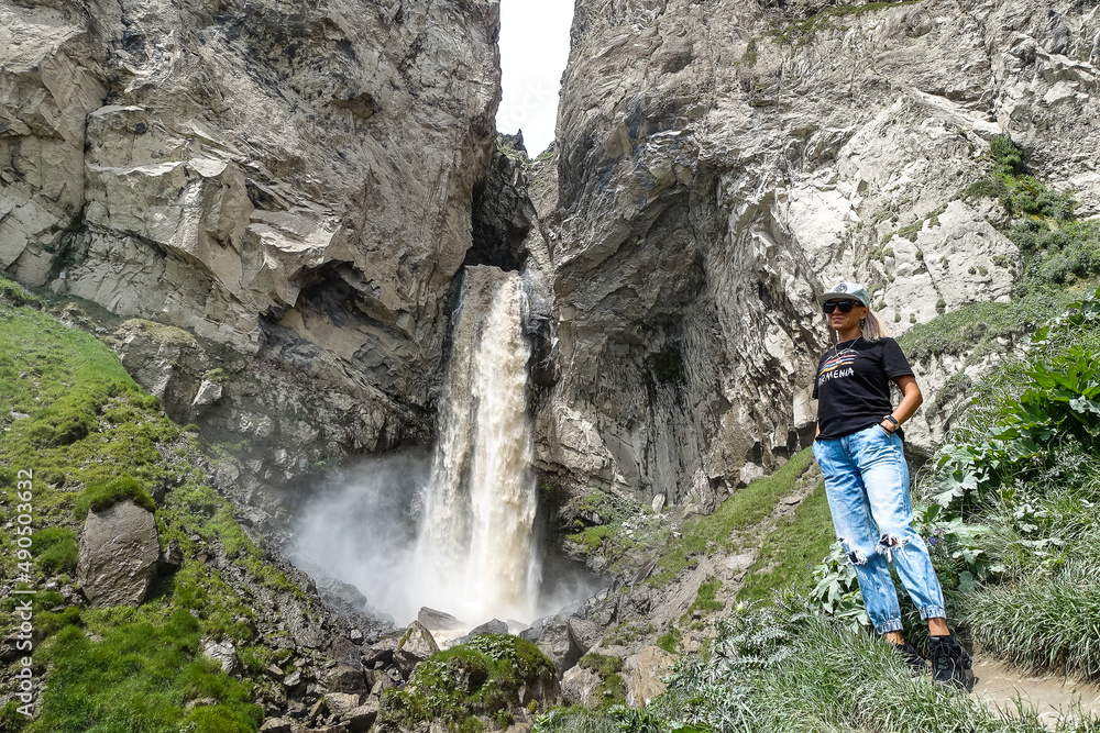 A girl at the Sultan-su waterfall surrounded by the Caucasus Mountains near Elbrus, Jily-su, Russia