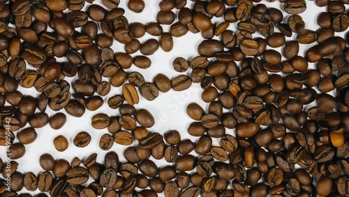 The coffee beans spin rotate quickly fast fly, dispart, splash to the sides with centrifugal coriolis force. The video is in reverse. Twist, create pattern, make design picture. Pressurized air wind. photo