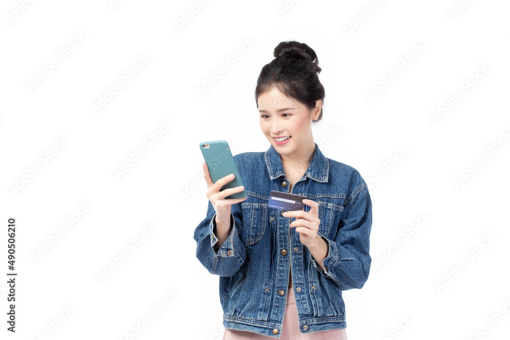 Portrait Asian happy young girl in jeans shirt smiling cheerful and showing plastic credit card while holding mobile phone isolated on white background. Shopping online concept. Portrait Asian happy young girl in jeans shirt smiling cheerful and showing plastic credit card while holding mobile phone isolated on white background. Shopping online concept.