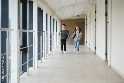 Cute pupils running down the hall at the elementary school © Serhii