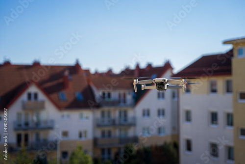 Dron w mieście, dron leci wsród bloków mieszkalnych.