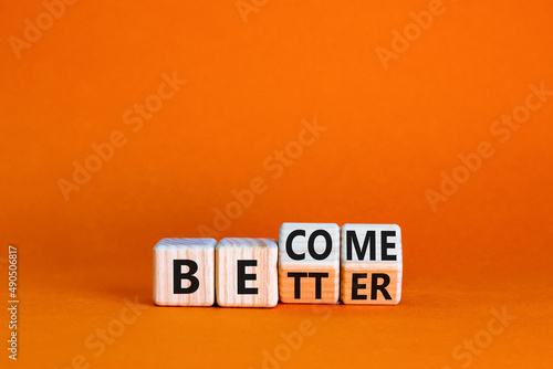 Become better symbol. Turned wooden cubes and changed the concept word Better to Become. Beautiful orange table orange background. Business become better concept. Copy space.