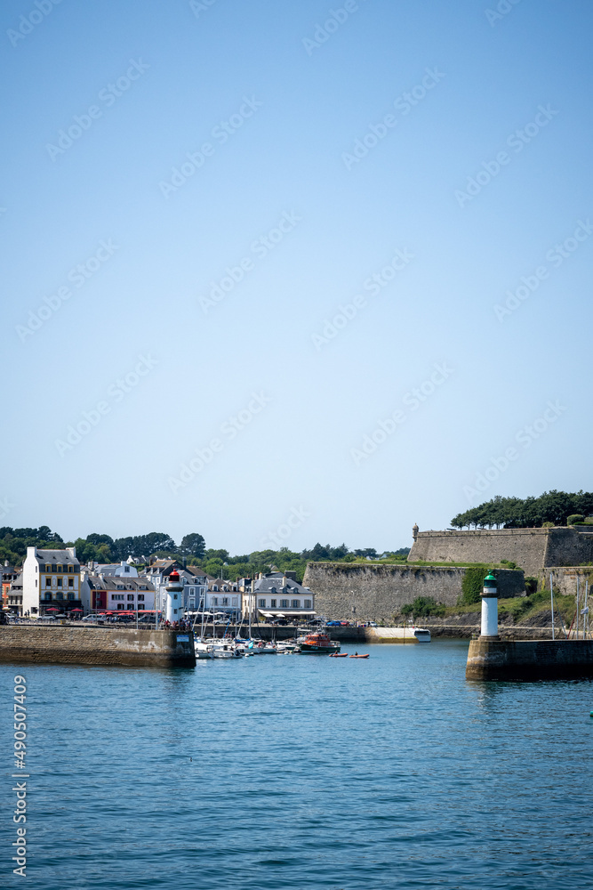 The harbor entrance of La Palais on the Belle-ile en mer with lighthouse and castle on a calm summer day.