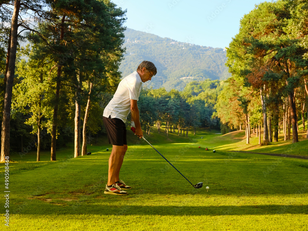 Golfer on a golf course, ready to tee off. Golfer with golf club hitting the ball for the perfect shot.