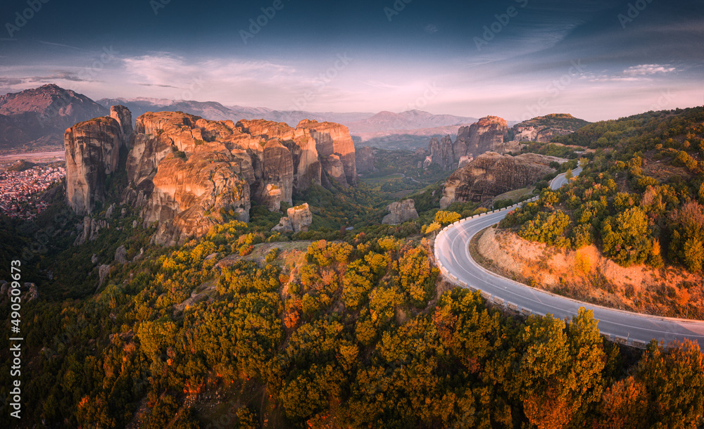 Inspirational aerial panoramic view of iconic and majestic Meteora monastery travel destination and winding road in Greece. Discover new tourist experience