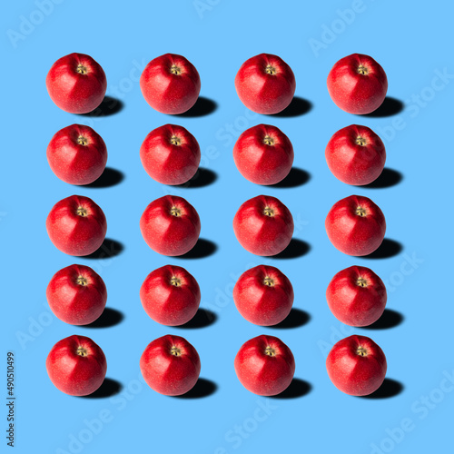Red apples with shadows on blue background, pattern