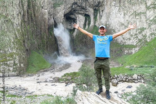 A man on the background of the Tuzluk-Shapa waterfall on the territory of Kabardino-Balkaria. Caucasian. Russia.