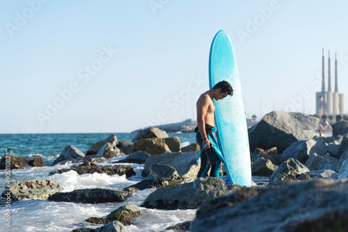 Fototapeta Naklejka Na Ścianę i Meble -  Handsome surfer man holding a surfer board at sea shore