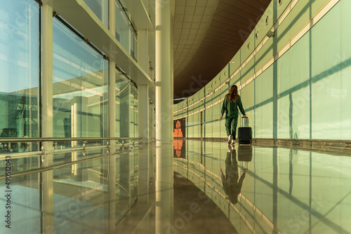 woman walks in the airport with her suitcase at sunrise