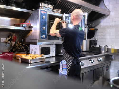 Cook working in a restaurant kitchen preparing the oven
