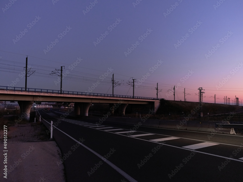 Railway bridge crossing a motorway at sunset