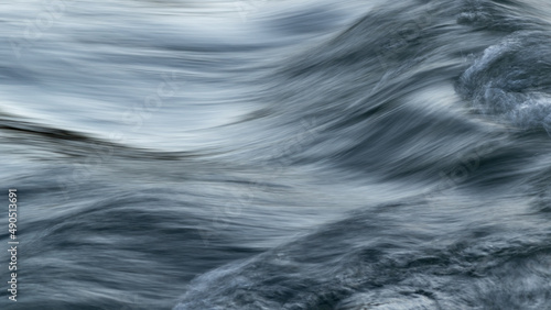 Rapid water flow in mountain stream with silky surface and motion blur - abstract landscape close up