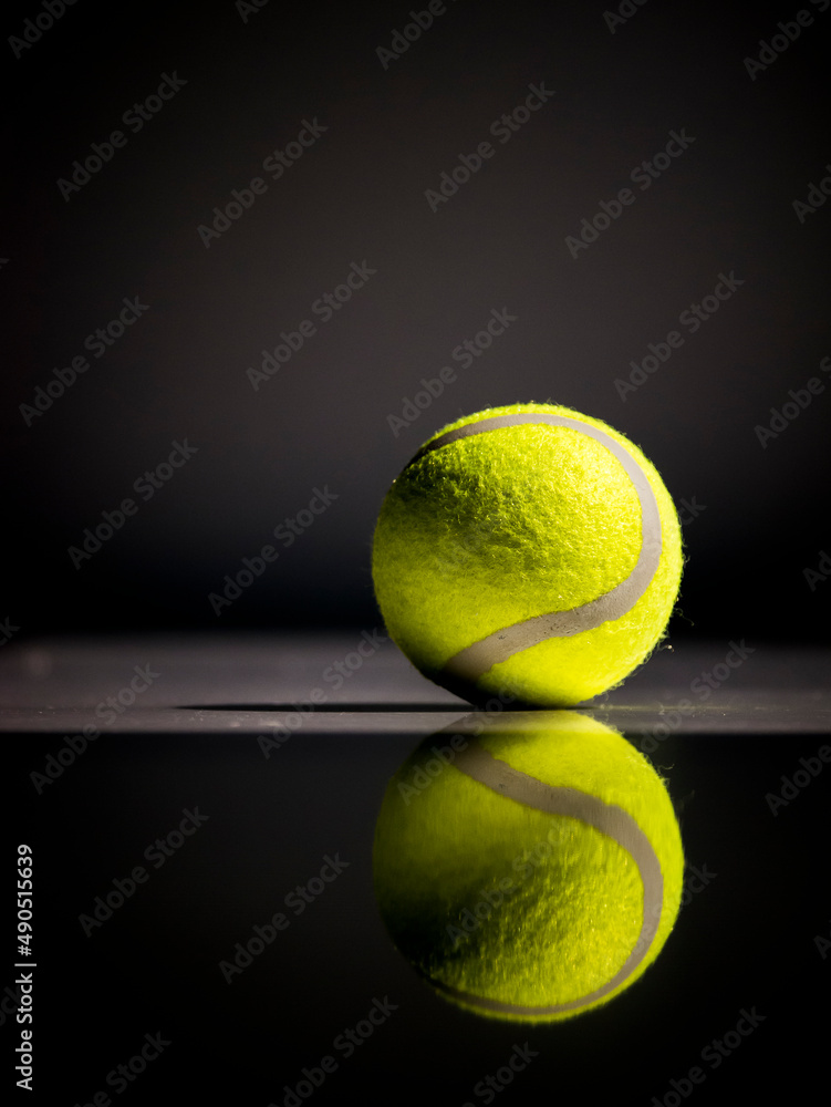 어둠 속에서 빛을 받아 빛나는 테니스 공