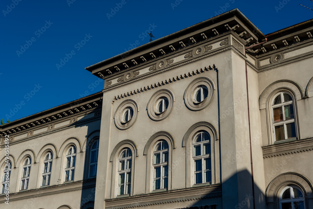 Wyższa Szkoła Administracji w Bielsku-Białej, okrągłe okna i bogate zdobienia. Niebieskie niebo.