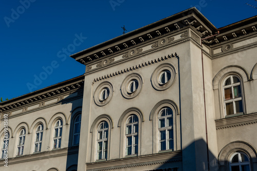 Wyższa Szkoła Administracji w Bielsku-Białej, okrągłe okna i bogate zdobienia. Niebieskie niebo.