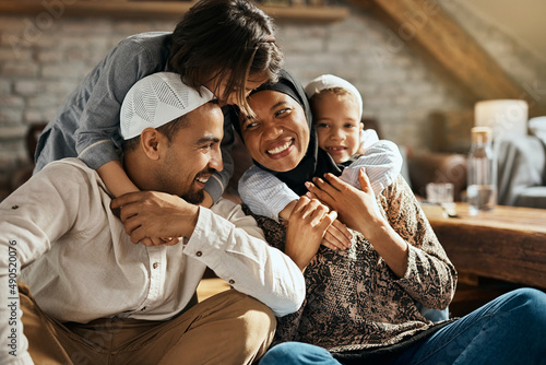 Happy Muslim kids embrace their parents and have fun at home.
