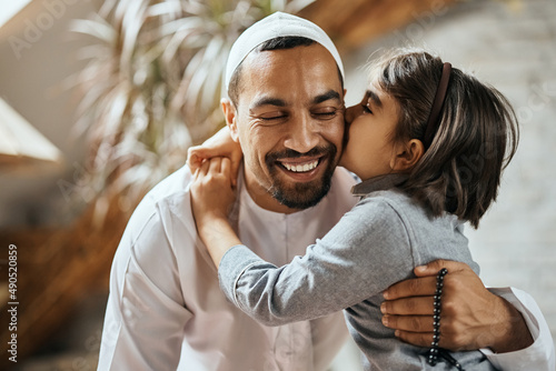 Cuadro en lienzo Affectionate Muslim girl kisses her father while embracing him at home