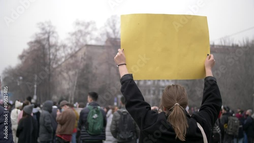 A girl with a placard protests at a rally on a city street.