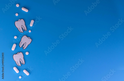 Pills and teeth on a blue background. Toothache concept. Copy space.