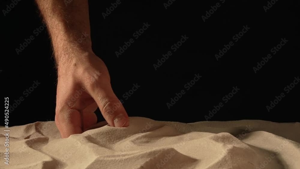 Man with handful of white dry sand in her hands, spilling sand through her fingers on black studio background. Close up of grains of pure natural mineral quartz in male hand. Slow motion. Man with handful of white dry sand in her hands, spilling sand through her fingers on black studio background. Close up of grains of pure natural mineral quartz in male hand. Slow motion.