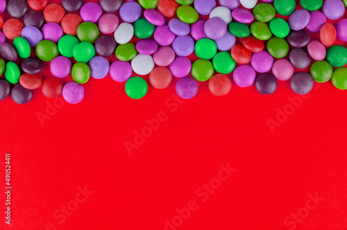 Multi-colored candies on a red background. Copy space.