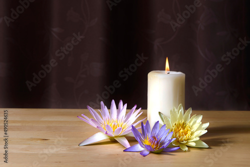 Burning candles and beautiful waterlily on a wooden floor.