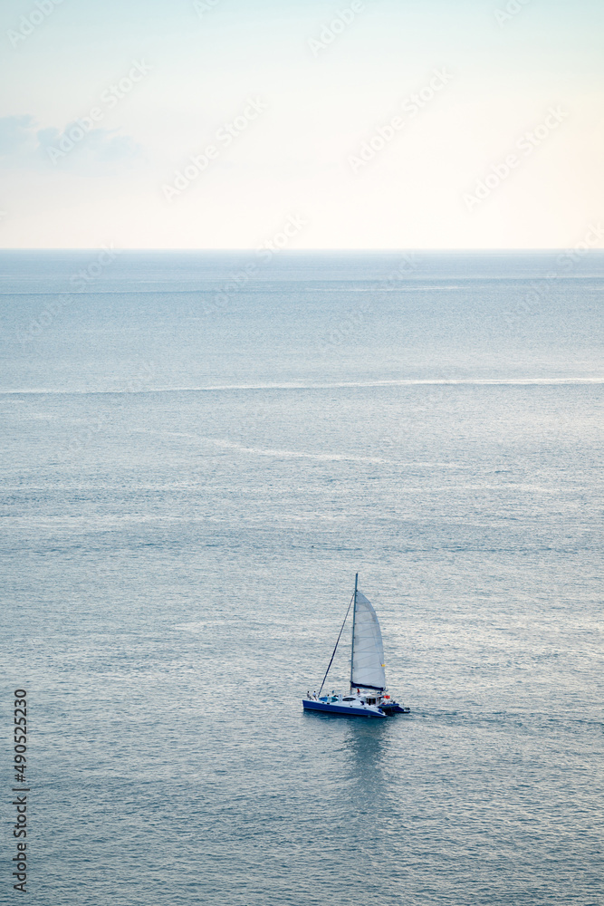 minimal Sailboat Yacht is saling on the calm sea, shoot this image from above of the mountain Phrom Thep Cape, Phuket Thailand with Tele lens.
