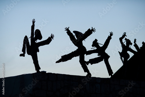 Silhouette metal cutouts of dancing Orthodox Jewish men on a rooftop in northern Israel.