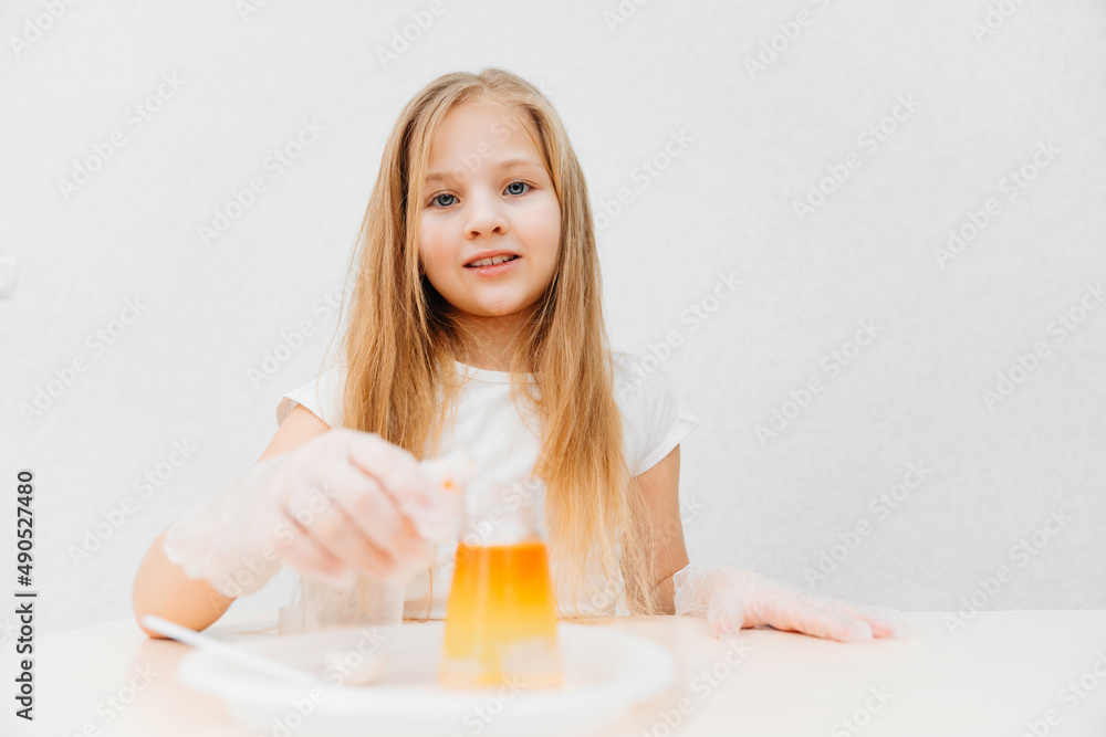 a cute little girl conduct an experiments at home. flask with colored liquid a cute little girl conduct an experiments at home. flask with colored liquid