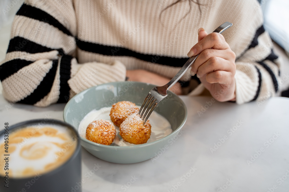 Close-up of the hands of a girl with a fork in her hands,curd syrniki on a plate Close-up of the hands of a girl with a fork in her hands,curd syrniki on a plate