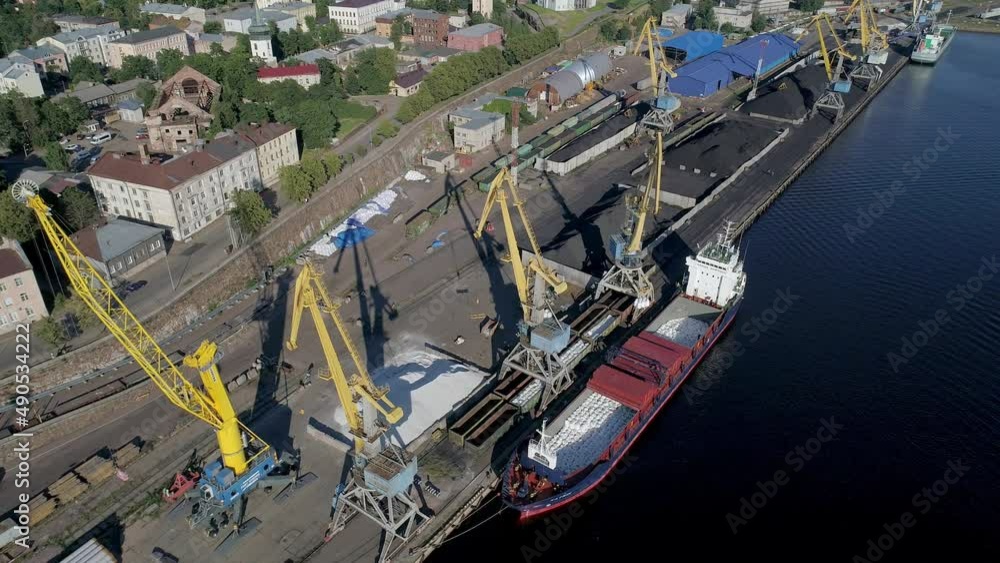 Aerial high angle view of dry cargo ship is loading in the port. Bulk carrier is in front of huge port cranes