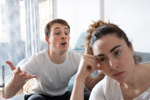 Angry man shouting to dispaired girlfriend. Couple cohabitation problems and toxic relationship concept. photo