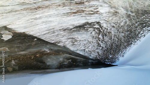 Fototapeta Naklejka Na Ścianę i Meble -  A huge ice wave froze in the mountains. View of the marble glacier. White snow, trails from people are visible. Tourists go to places and take photos. The ice has an unusual shape. Kazakhstan, Almaty