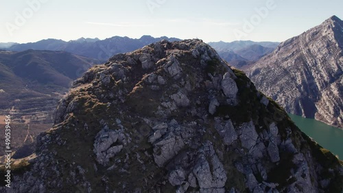 Drone above a rocky mountain summit at a really high height. Mountain top, peak covered by bushes. Brown and grey colours below a clear pale blue sky at plain daylight. León, Spain.    photo