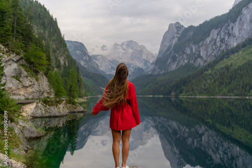 Beautiful girl in a red dress in the mountains near the lake